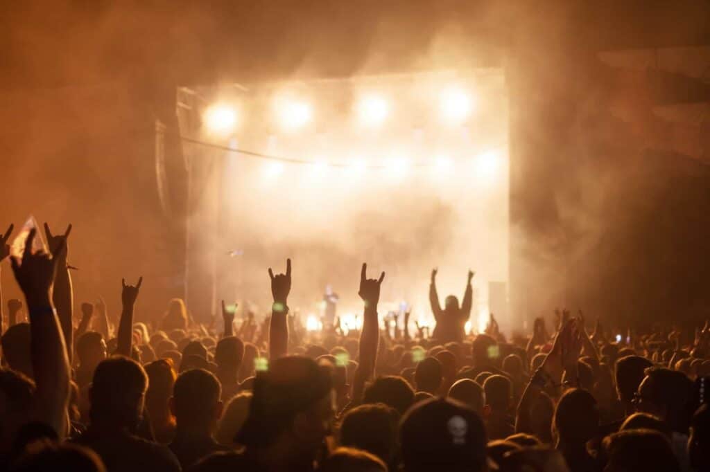 silhouettes of concert crowd in front of bright stage lights